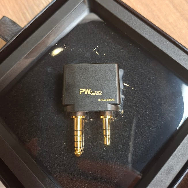 PW Audio adapter on a black surface with a wooden background